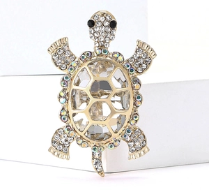 Macro shot of gold turtle brooch featuring a large clear crystal and pavé rhinestones