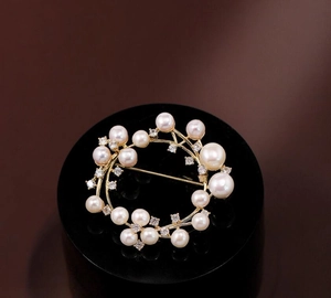 Macro detail of a gold pearl wreath brooch with white zircons on a black display stand
