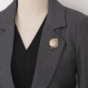 Detail of elegant double leaf brooch with pearl on a grey suit lapel for professional style
