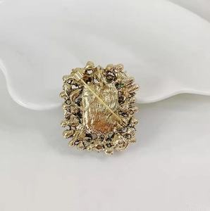 Detailed back view of vintage square gold brooch showing security pin and metal hollow carvings