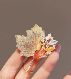 Macro shot of maple leaf brooch with orange crystals and detailed gold veins