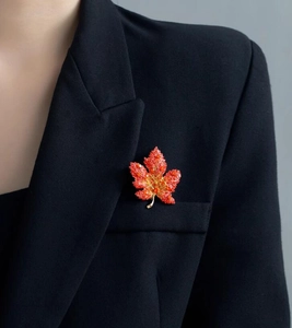 Detailed view of red gradient maple leaf brooch pinned on a black professional suit jacket