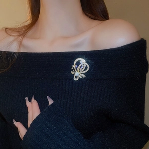 Elegante goldene Schleifenbrosche mit Kristallen und Perle auf schwarzem Pullover