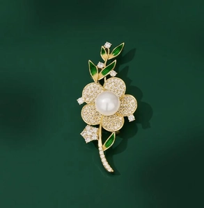 Gros plan détaillé d'une broche florale avec perle, émail vert et zircons brillants