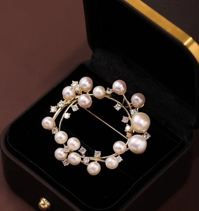 Detailed macro view of a circular pearl wreath brooch with gold metal and zircon accents