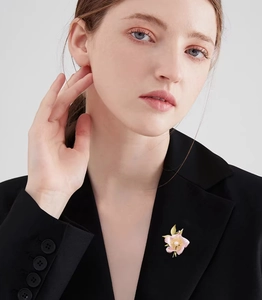 Detail of pink enamel camellia brooch with pearl accent on a black suit lapel