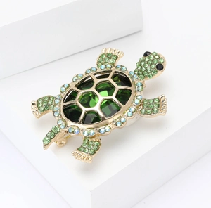 Detail of golden turtle brooch with green crystal shell and sparkling rhinestones