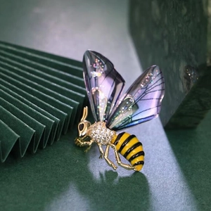 Exquisite gold bee brooch with purple wings and sparkling crystals on a dark background