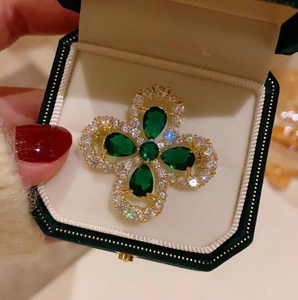 Broche trèfle émeraude vintage avec base dorée et diamants dans un écrin à bijoux