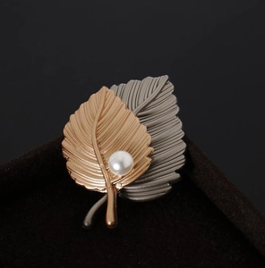 Close-up of vintage double leaf brooch with rose gold finish and white pearl detail