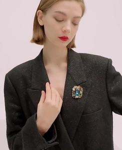 Detail of luxury vintage square brooch with navy gemstone and pearls on a black suit