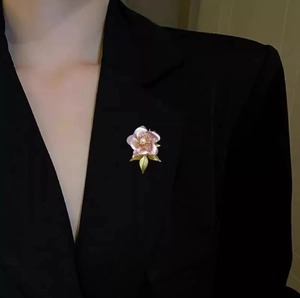 Elegant pink camellia flower brooch with pearl accent on a black blazer lapel