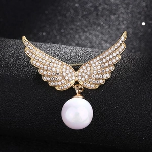 Élégante broche ailes d'ange avec strass brillants et perle blanche sur base dorée