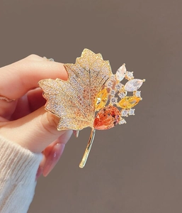 Detail of vintage maple leaf brooch featuring gold alloy, crystals, and amber gems