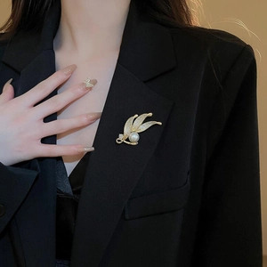Eleganter Blatt-Brosche in Gold mit weißer Perle und Zirkonia auf schwarzem Blazer-Revers