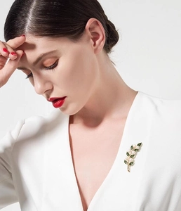 Élégante broche feuille dorée avec émail vert et perles blanches sur haut blanc
