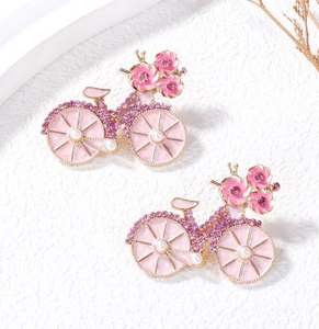 Detail van roze fietsbroche met kleine paarse strass-steentjes en witte parels