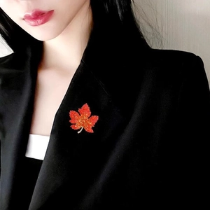 Elegant red maple leaf brooch with gold stem pinned on a black suit lapel for women