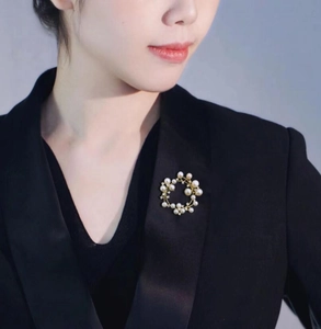 Macro detail of a gold floral wreath brooch with white pearls and sparkling rhinestones