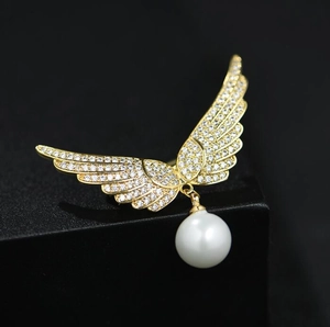 Broche ailes d'ange dorées avec strass étincelants et pendentif en perle blanche