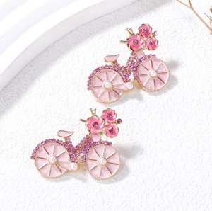 Detail van vintage fietsbroche met roze emaille bloemen en paarse kristallen op de wielen