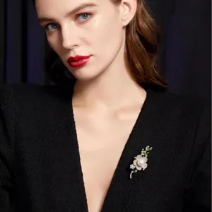 Broche fleur élégante avec perles et cristaux sur une veste classique en tweed noir
