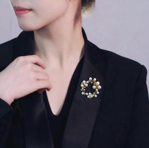 Elegant circular pearl and crystal wreath brooch worn on a classic black blazer lapel