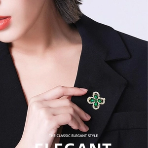 Élégante broche trèfle à quatre feuilles avec émeraude et cristaux sur revers noir