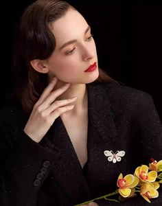 Detailed view of an elegant butterfly brooch with pearls on a black tweed blazer jacket