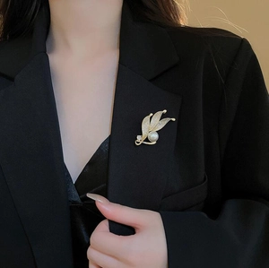 Elegante goldene Blatt-Brosche mit Kristallen und Perle am schwarzen Revers