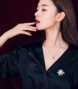 Detailed close-up of a flower pearl brooch and minimalist jewelry worn by a model