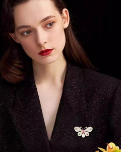 Close-up of elegant butterfly brooch with colorful crystals and pearl on black blazer
