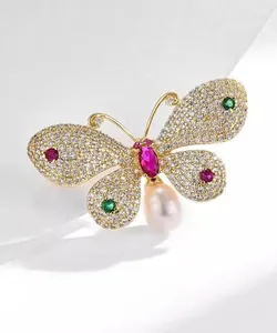 Macro view of butterfly brooch with colorful crystals and teardrop pearl pendant