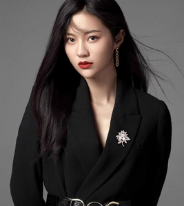 Detail of flower pearl brooch and gold chain earrings on a black tailored blazer