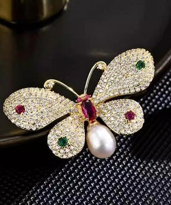 Macro detail of butterfly brooch with colorful crystals, sparkling zircons and a pearl drop