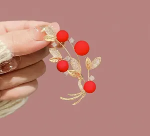 Elegant gold brooch featuring red berries and sparkling white zircons on a coat