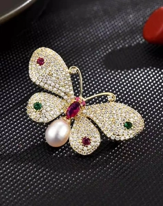 Macro detail of butterfly brooch with colorful crystals, sparkling zircons and a white pearl