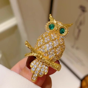 Detaillierte Eulen-Brosche mit weißen Zirkonia und grünen Edelsteinaugen auf Goldzweig