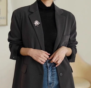 Close-up of floral pearl brooch with silver petals on a dark gray suit blazer jacket