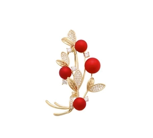 Detailed macro view of elegant gold-plated berry brooch with red pearls and crystals