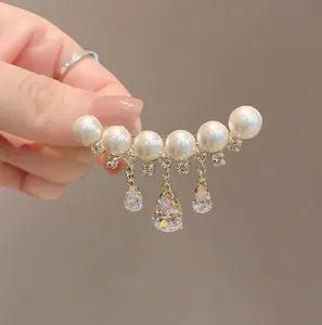 Détail de la broche dorée élégante avec perles blanches et gouttes de zircon brillantes