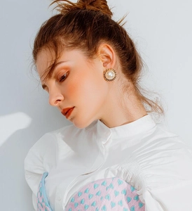 Close-up of elegant large pearl earring with gold rope frame worn by a female model