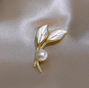 Élégante broche en forme de feuille dorée avec perle et zircons sur soie satinée