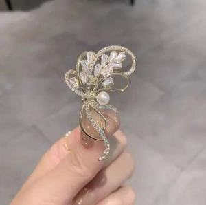 Gros plan détaillé d'une broche papillon dorée avec des cristaux brillants et une perle