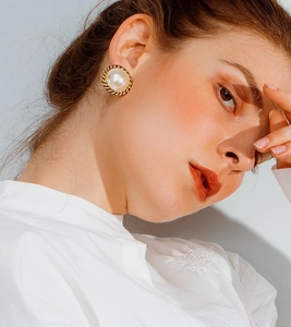 Close-up of vintage faux pearl stud earrings with golden twisted rope metal borders
