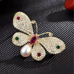Elegant butterfly brooch with colored crystals and a pearl drop on a gold-plated base