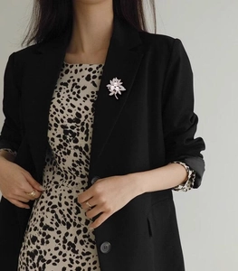 Detail of elegant flower brooch with pearls and crystals on a black suit blazer