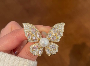 Close-up of luxury butterfly brooch with white pearls and sparkling zircons on a sweater