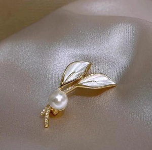 Gros plan d'une élégante broche feuille en perles sur un tissu en soie luxueux