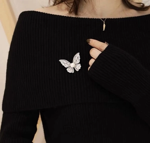 Close-up of sparkling butterfly brooch with pearl detail on a black knit sweater
